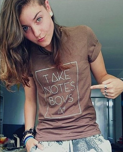 Model wearing brown v-neck 'take notes boys" t-shirt by Androgynous Fox
