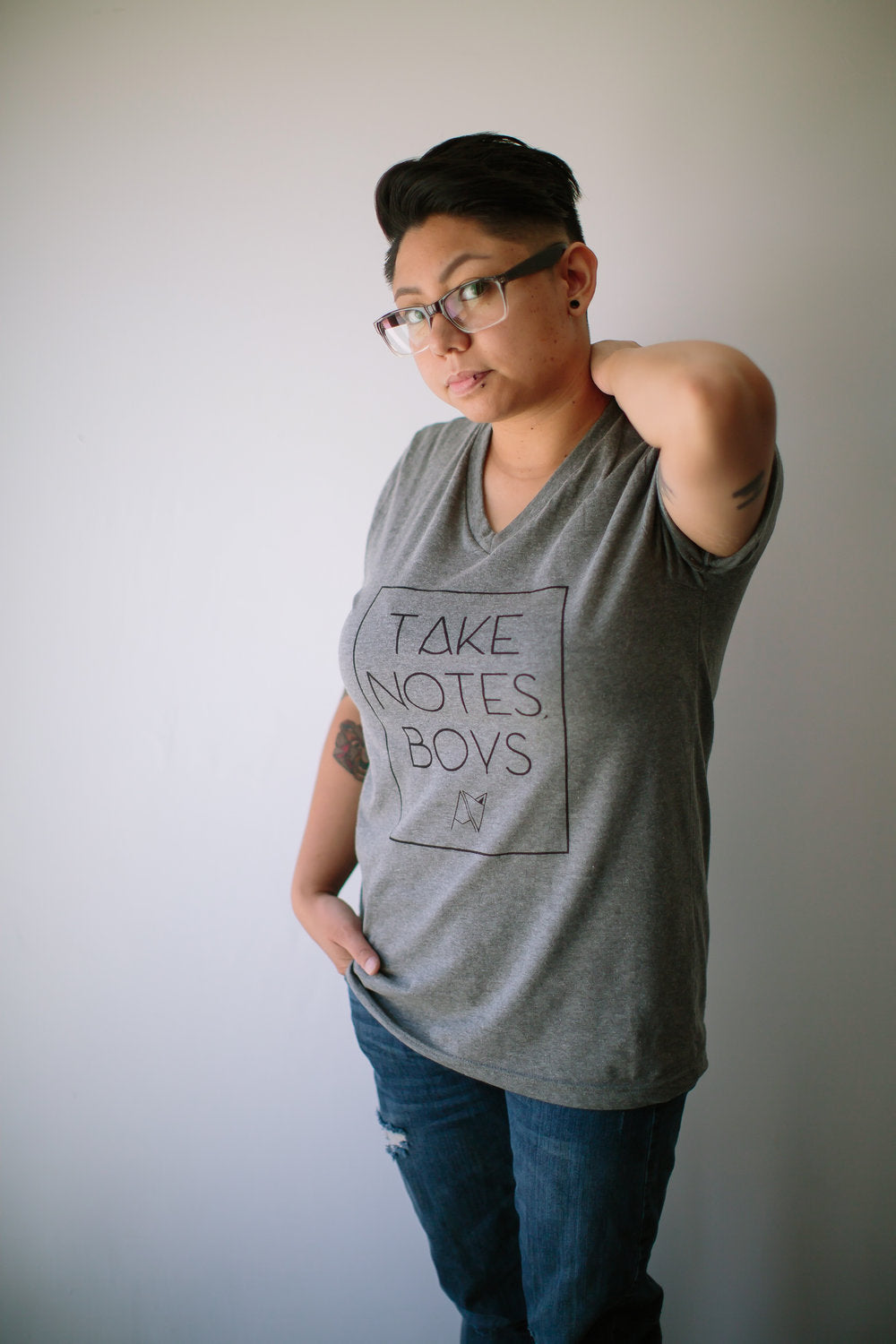 Model wearing grey v-neck 'take notes boys" t-shirt by Androgynous Fox