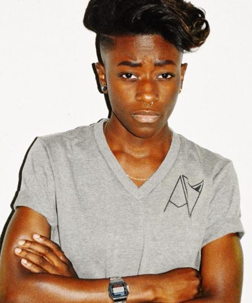 Model wearing grey v-neck badge logo tee by Androgynous Fox. 