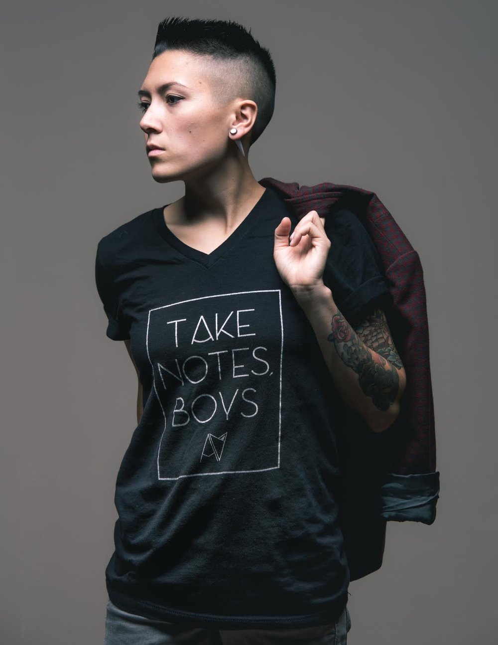 Model wearing black v-neck 'take notes boys" t-shirt by Androgynous Fox.